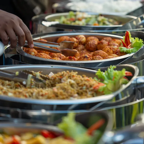 Warme schalen op een buffet, een hand schept op met een tang