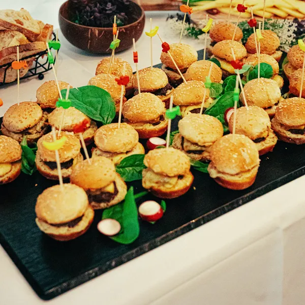 Mini-burgers met prikkers op een leisteen plank