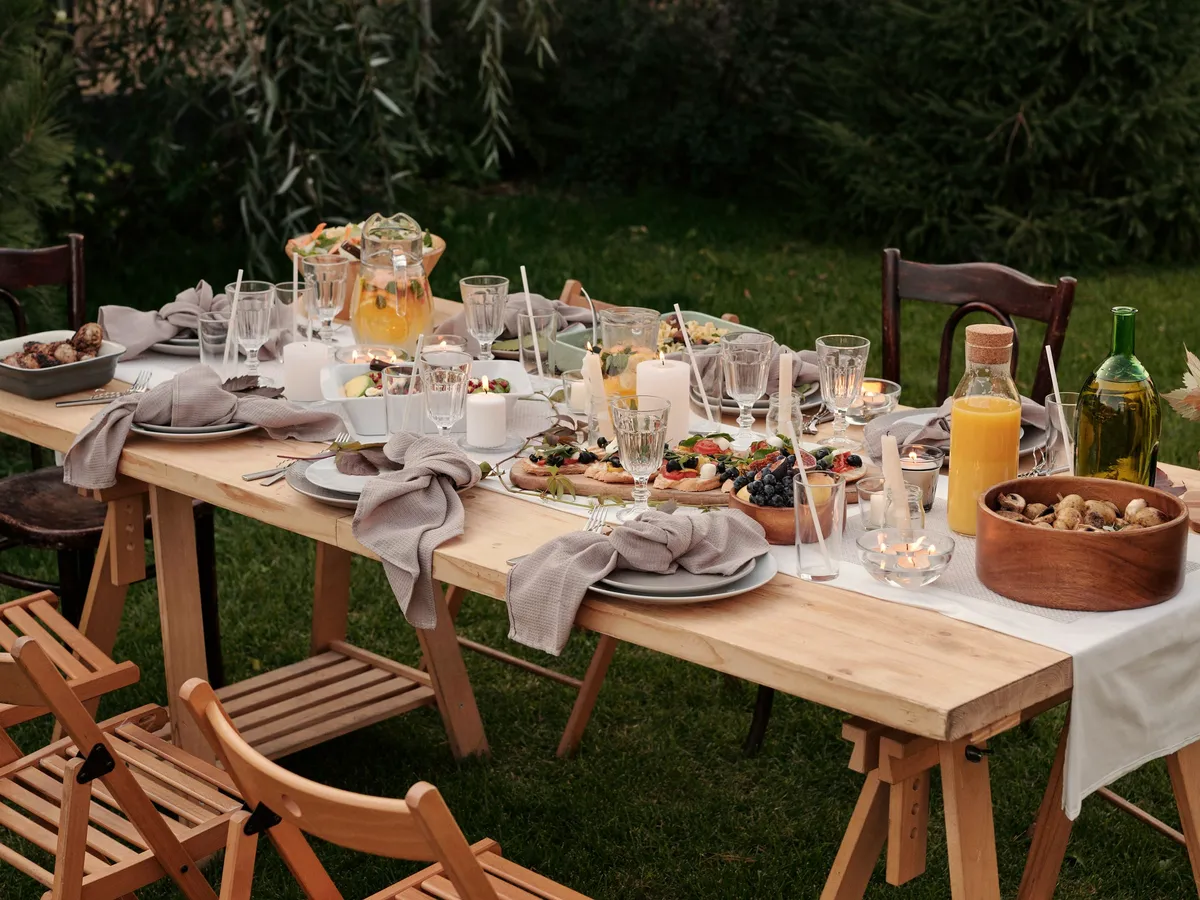 Gedekte lange tafel in een tuin, met kaarsen en schalen