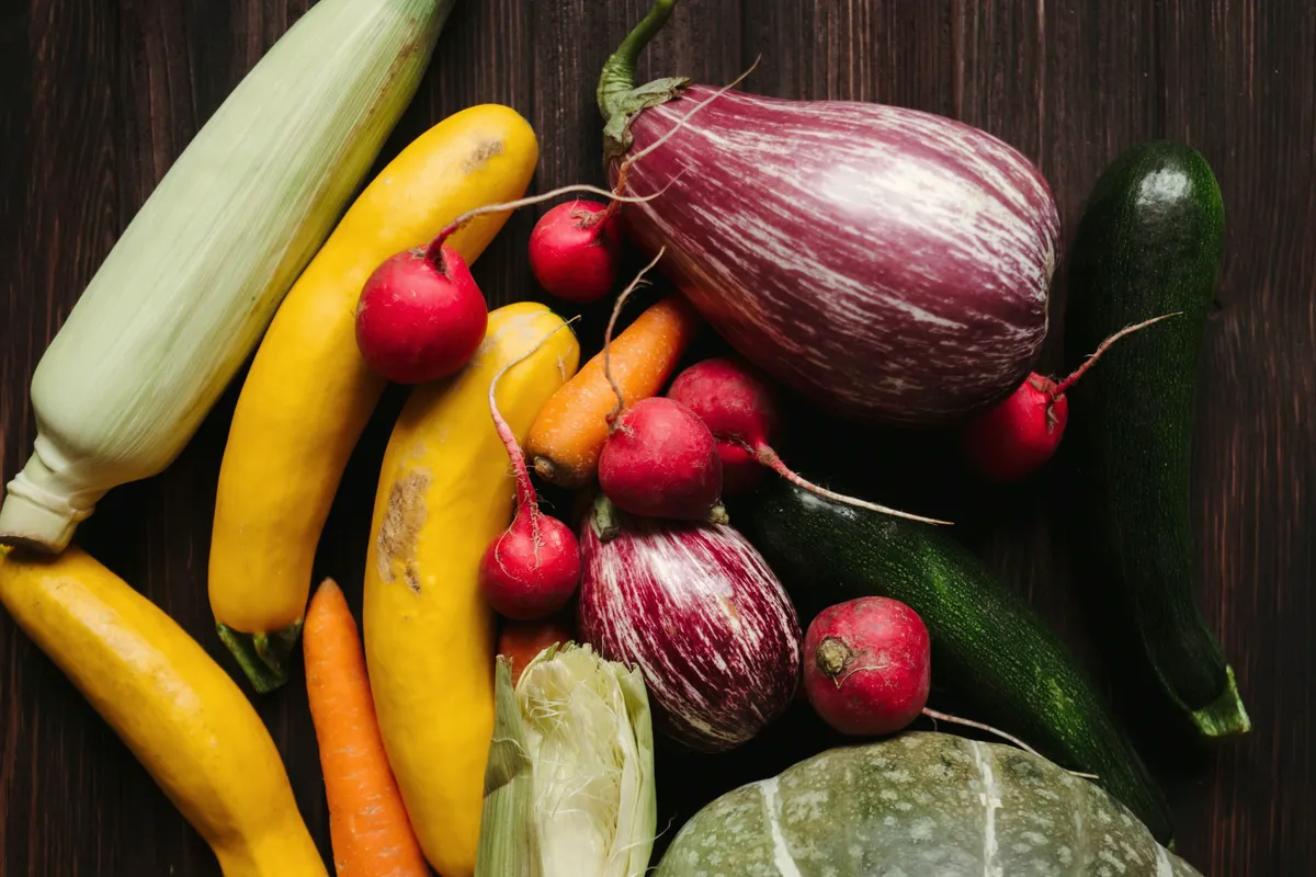 Aubergine, courgette, radijs, wortel en pompoen op een houten tafel